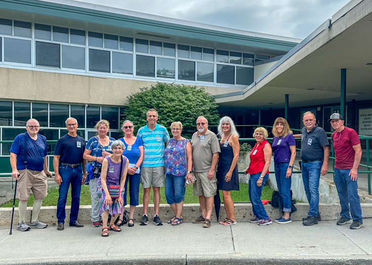 Group photo of alumni in front of school