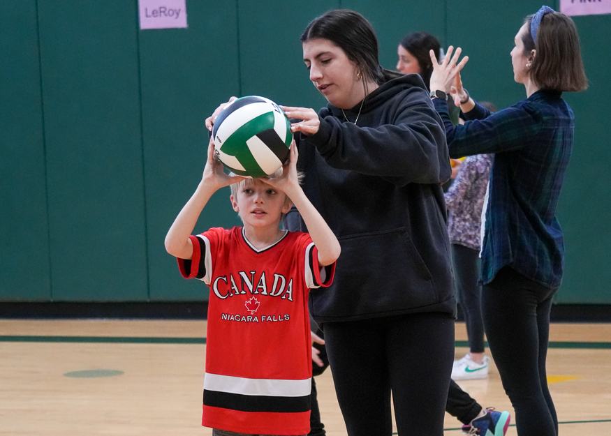 Student teaches child volleyball